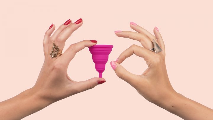 Two hands holding a reusable menstrual cup